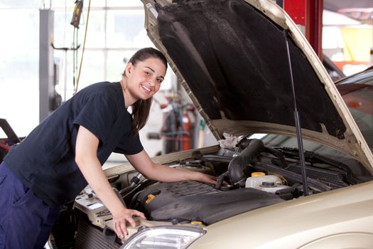 Portrait of a happy mechanic woman working on a car in an auto repair shop