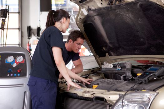 A man and woman mechanic working on a car in a auto repair shop