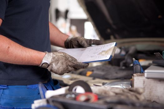 Detail of a mechanic holding a service order with a dirty glove on