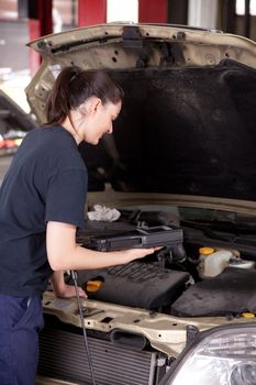 A happy woman mechanic with a smile using an engine diagnostics tool