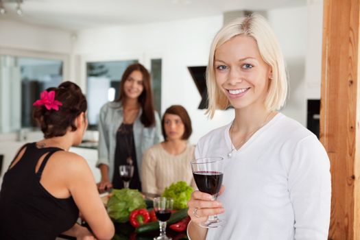 Smiling woman holding glass at party with female friends in background