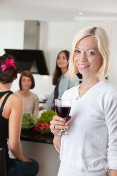 Portrait of pretty woman holding glass wth female friends in background