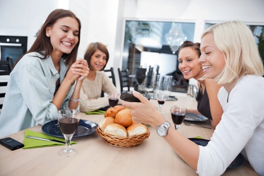 Women showing something to her friends on mobile phone at dining table - Shallow Depth of field critical focus on phone.