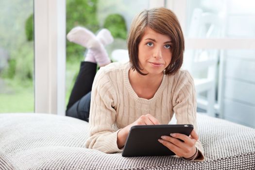 Portrait of young woman using digital tablet while lying on couch