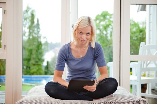 Portrait of smiling young woman sitting on couch and using digital tablet