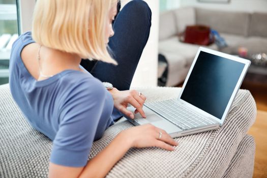Blond woman using laptop on couch