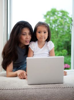 Mother and daughter using computer together in a home interior