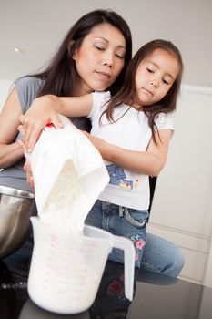 Mother and daughter baking together, measuring out dry ingredient