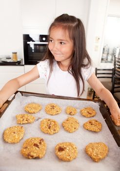 Young girl with cookie sheet filled with raw cookies