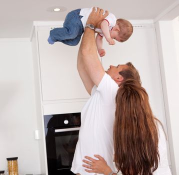 Happy playful family at home, mother and father throwing son in the air