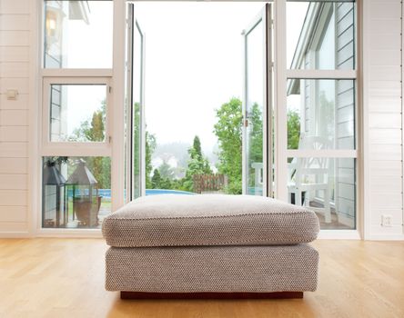 A large chair cushion in front of a large open window