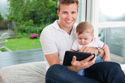 Portrait of smiling man using digital tablet while sitting with child