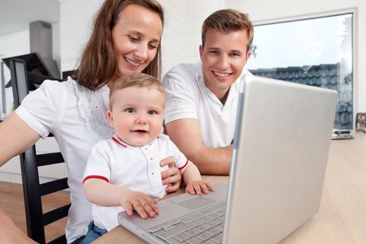 Family of three using a laptop at home