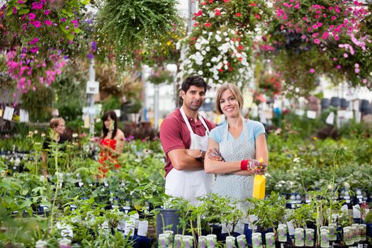 Portrait of florists at greenhouse with people in background