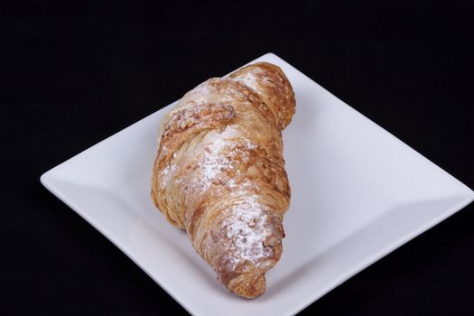 fresh almond croissant isolated on a black background