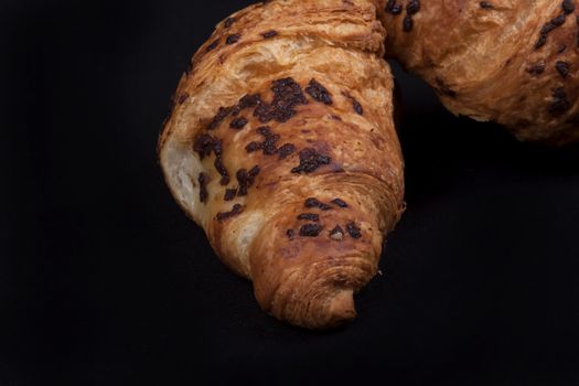 fresh chocolate croissant isolated on a black background