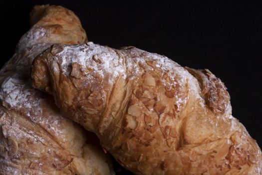 fresh almond croissant isolated on a black background
