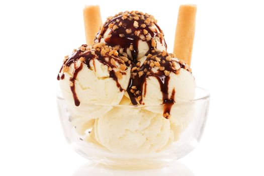 vanilla flavor ice cream in a glass bowl with waffles and chocolate sauce and brittle on white background