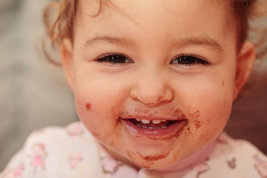 a beautiful baby smailing with a dirty mouth of chocolate