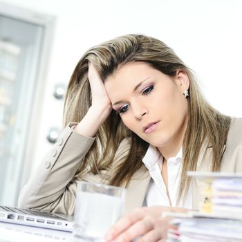 young woman stressed at work, taking an aspirin cahet