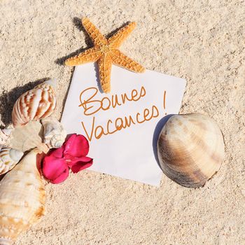 blank paper on white sand beach with starfish and shells like summer vacation background