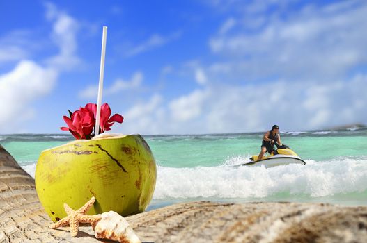 Coconut with drinking straw on a palm tree at the sea and jetski time