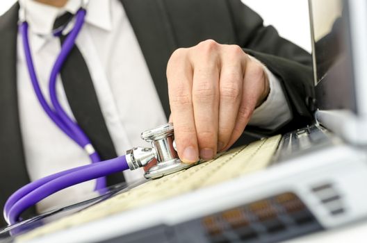 Close up of repairman holding stethoscope on his old laptop keyboard. 