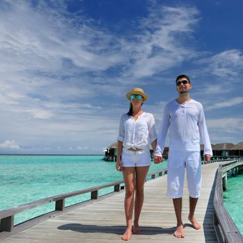 Couple on a tropical beach jetty at Maldives