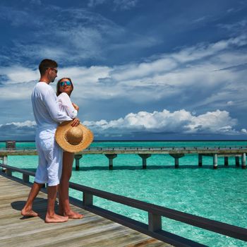 Couple on a tropical beach jetty at Maldives