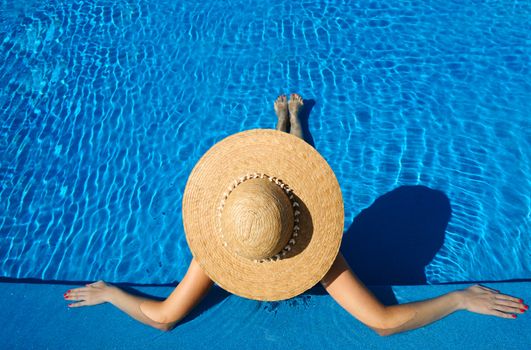 Woman in hat relaxing at the pool 