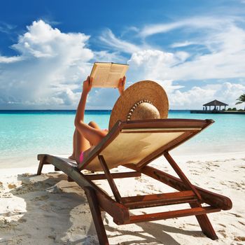 Young woman reading a book at the beach