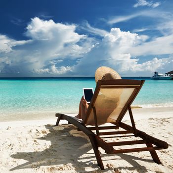 Young woman in hat with tablet pc at the beach