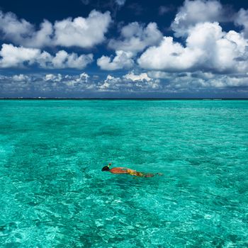 Man snorkeling in crystal clear turquoise water at tropical beach