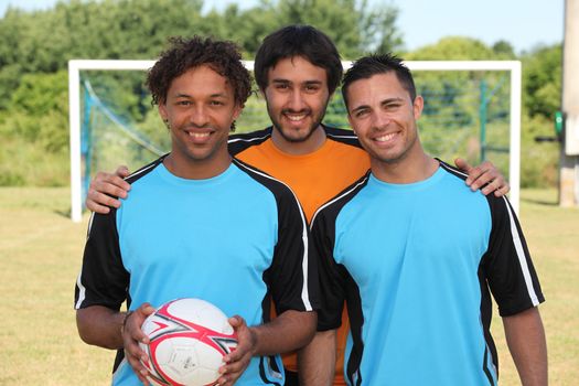 Three young footballers in front of goal