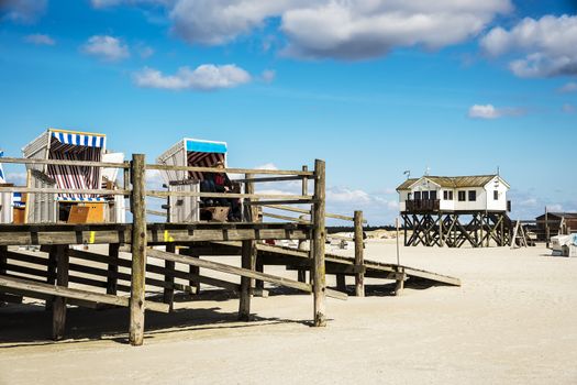 View of building and beach chairs to the sandy beach of St. Peter-Ording at the North Sea in Germany on a sunny day in spring