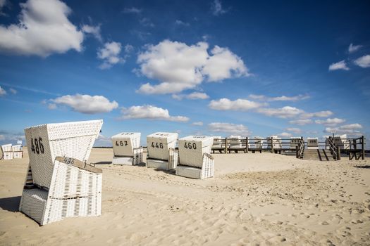 Beach chairs on a sunny day with clouds in the spring at the North Sea in St. Peter-Ording, Germany