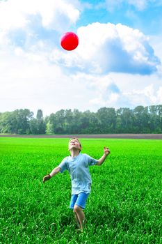 boy play with a ball in the summer field