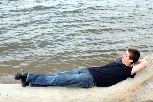 happy young man lying near the water