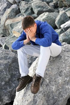 sad teenager sitting on the rocks