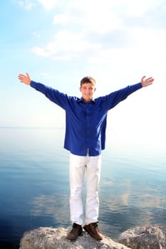 happy young man with hands up on the seaside background