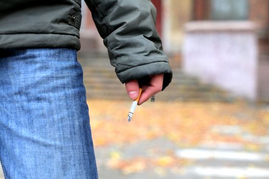 man holding cigarette in the hand closeup outdoor