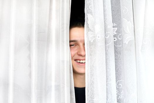 cheerful teenager look out of the curtains