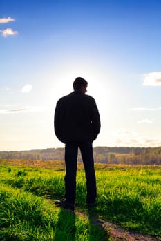 man silhouette in the summer field against the sunlight