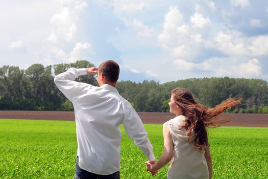 happy young man and teenage girl in the summer field