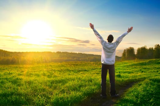 happy man with hands up on sunset background