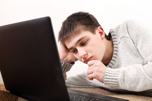 pensive young man with notebook on sofa