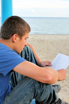 teenager looking on sheet of paper on the empty beach