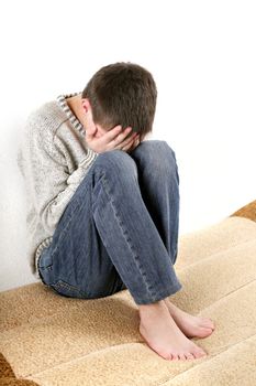 sad teenager sitting on the bed in home interior