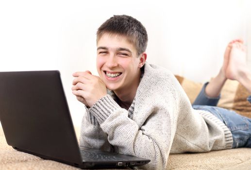 happy young man with notebook on sofa