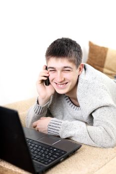 happy teenager with notebook talking on mobile phone in home interior